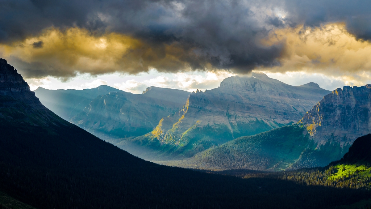 蒙大拿州冰川国家公园的洛根山脉 早晨与太阳穿过山谷和云层4K壁纸